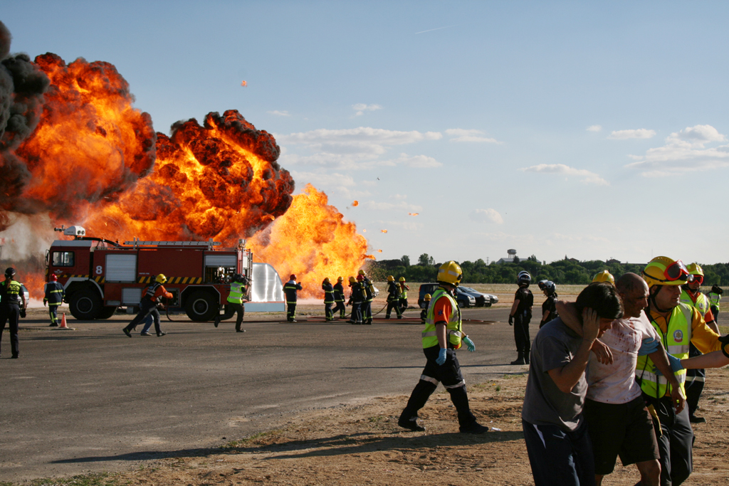 Explosión y llamas. Coche de bomberos. Sanitarios cargando pacientes leves
